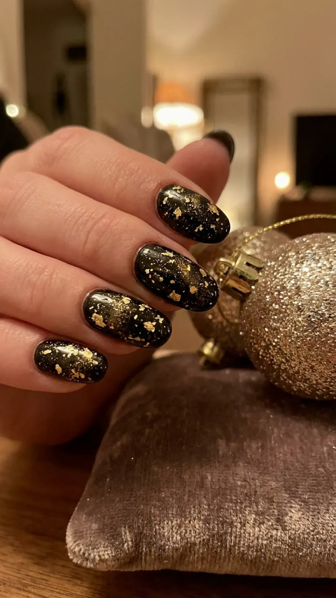 Stunning nail design with a deep black base splattered artistically with gold glitter, resembling a starry night sky, ideal for festive seasons.