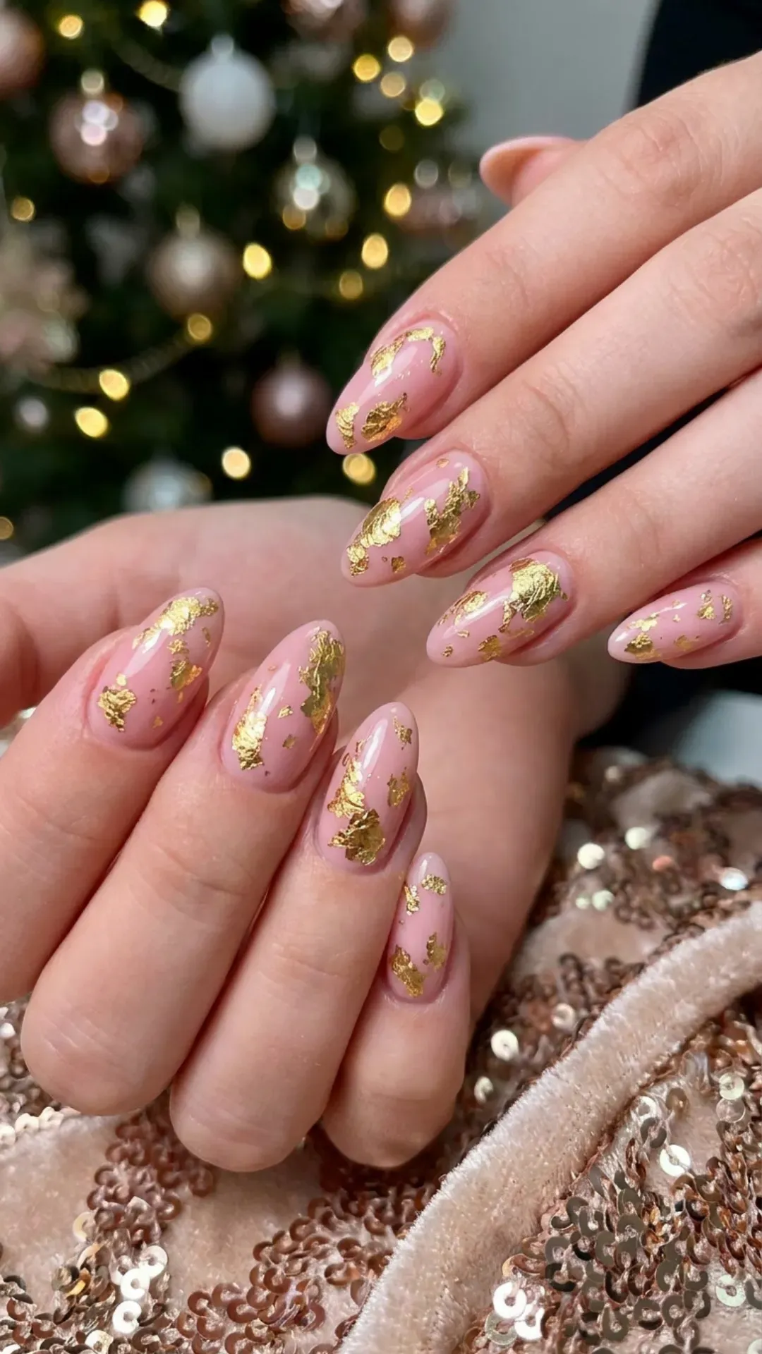 Fashion-forward pink nails accented with golden foil pieces, adding a touch of luxury and sparkle, the metallic highlights offer a glamorous contrast against the soft pink base for the holiday season.