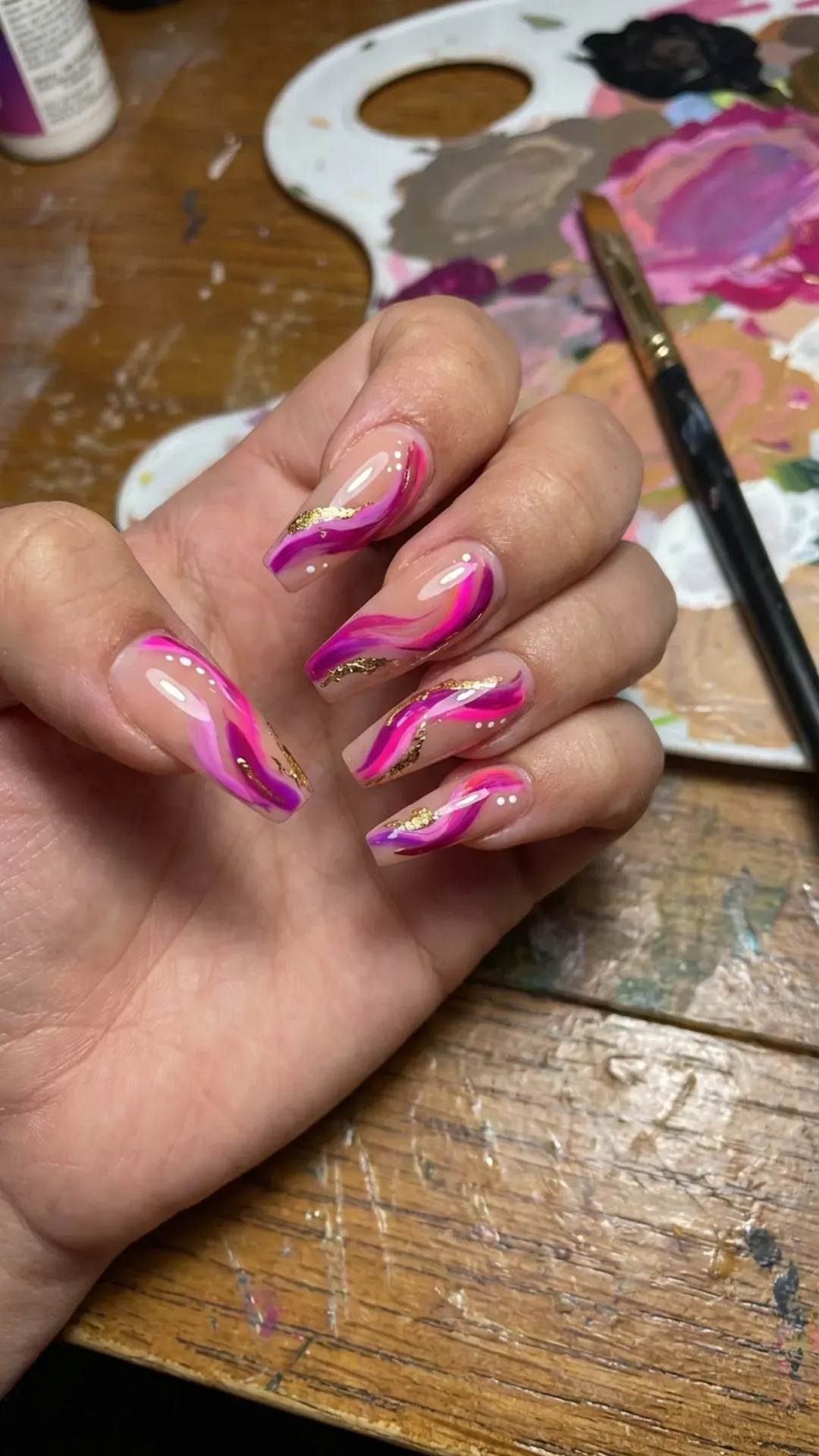 Coffin nails with an artistic flair, featuring swirls of vibrant pink over a nude base, reminiscent of abstract art for your fingertips.