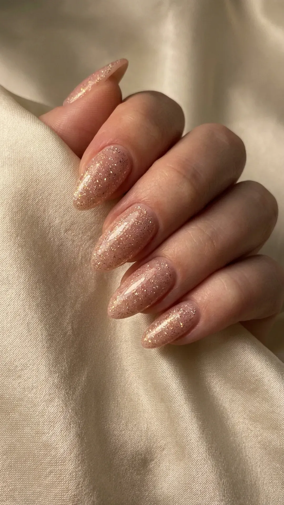  Nude pink nails with a shimmering glitter overlay that catches the light beautifully, perfect for a glamorous and trendy look.