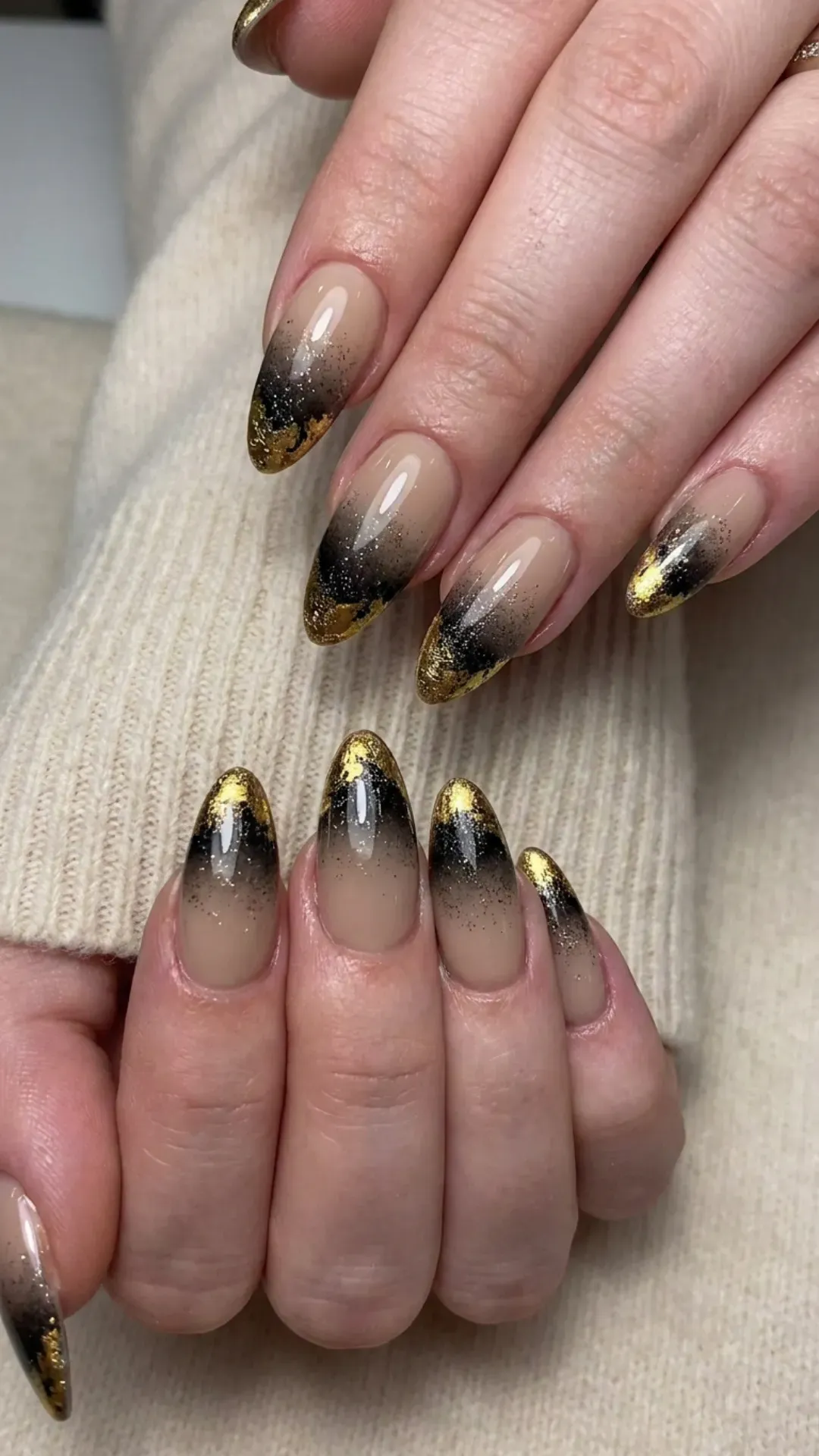 Subtle nude nails with a striking black to gold gradient effect, adorned with a touch of glitter for a sophisticated and contemporary appearance.