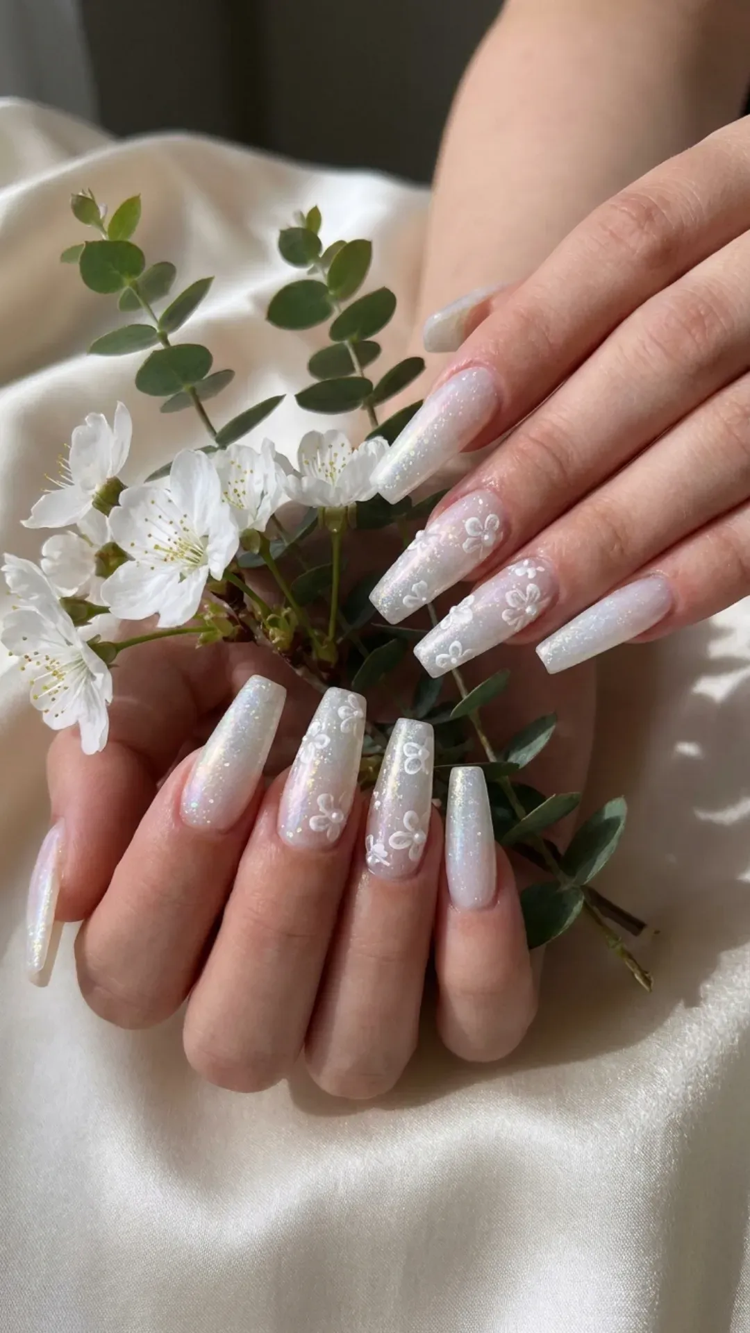 Bridal-inspired coffin nails adorned with delicate white flowers and subtle glitter, perfect for a springtime event or a romantic, elegant look.