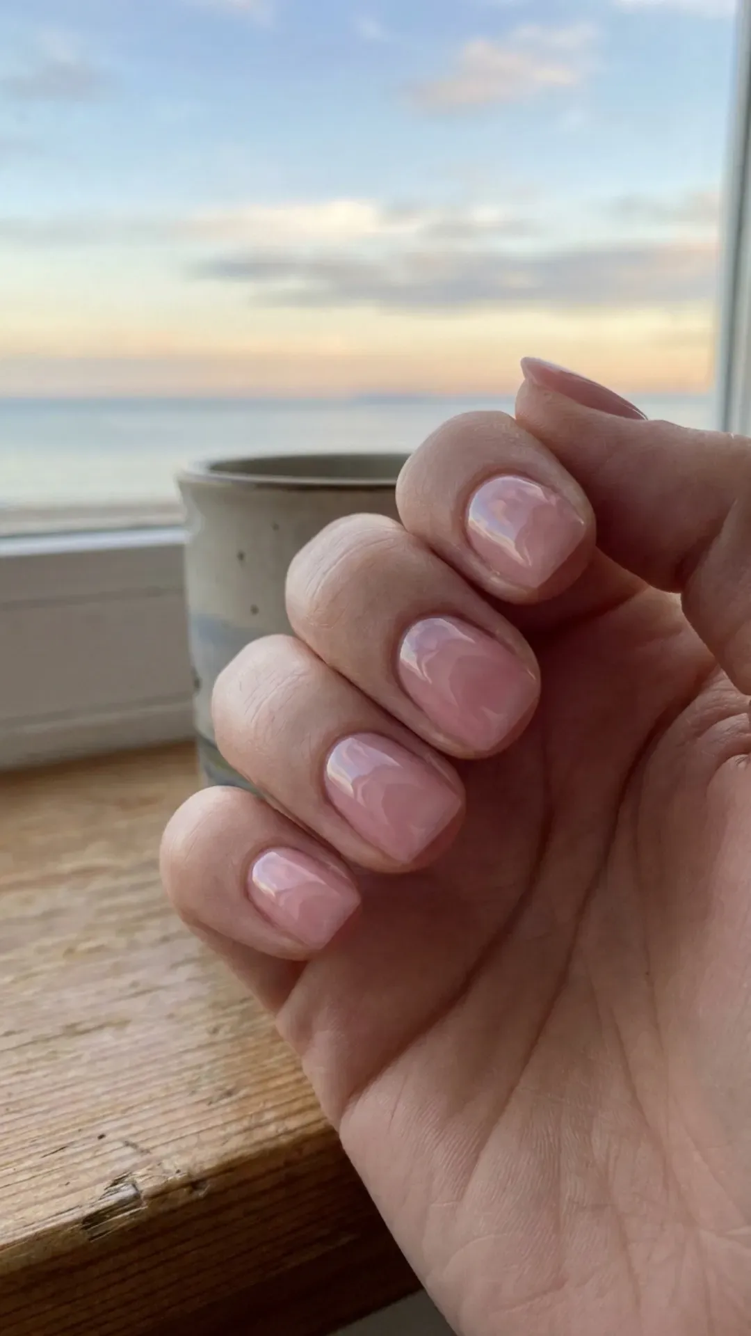 Glossy, smooth nails painted in a tranquil shade of pink, reflecting the serene beauty of a peaceful morning sky