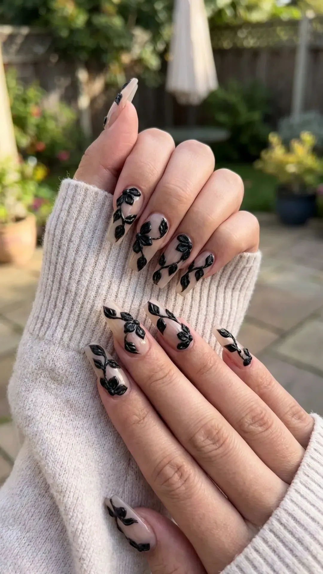 Unique coffin nails with sculptural black floral accents over a sheer base, offering a sophisticated and artistic nail art option that's sure to be a conversation starter this spring
