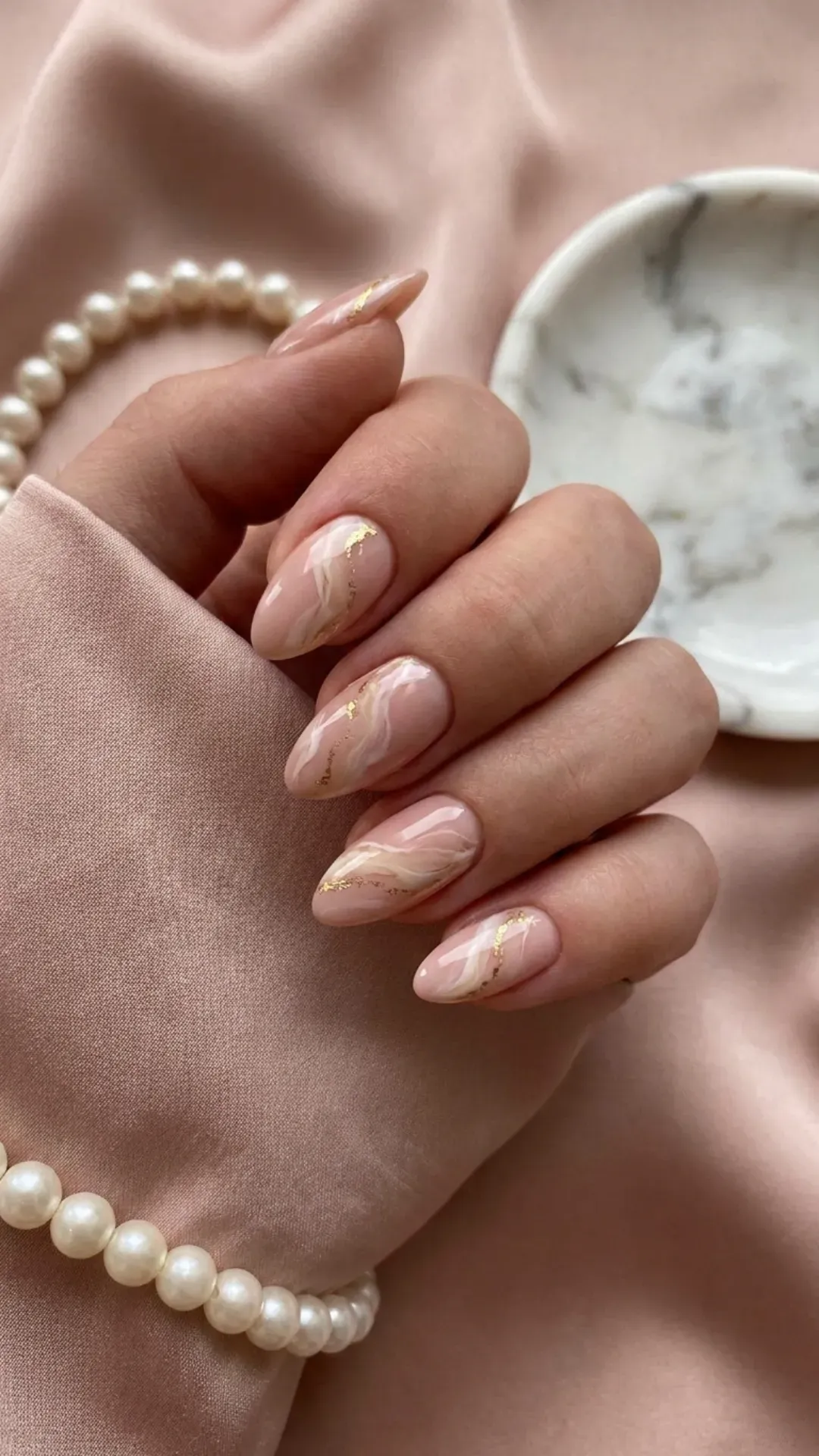 Soft nude pink nails with a luxurious marble effect, creating an elegant and sophisticated look with intricate white veining details.
