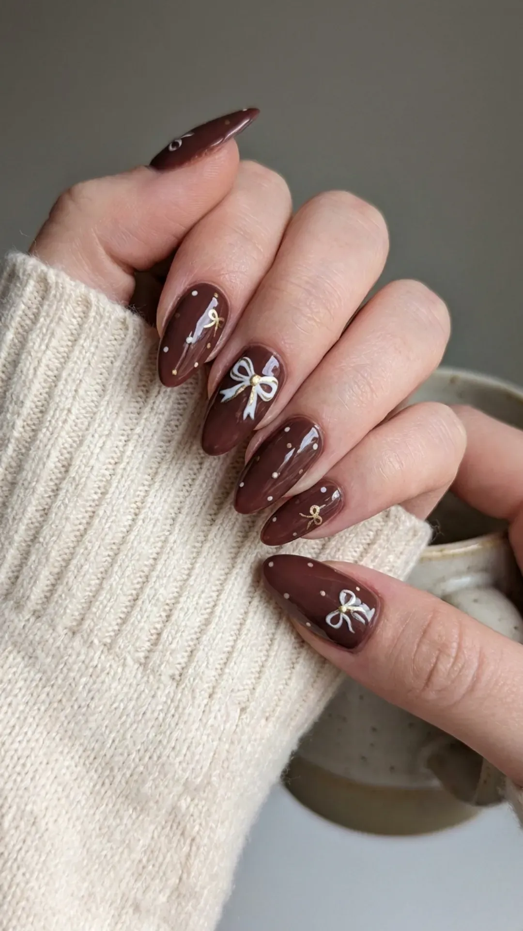 Cherry mocha nails decorated with tiny hand-drawn bows and polka dots, adding a playful and elegant touch.