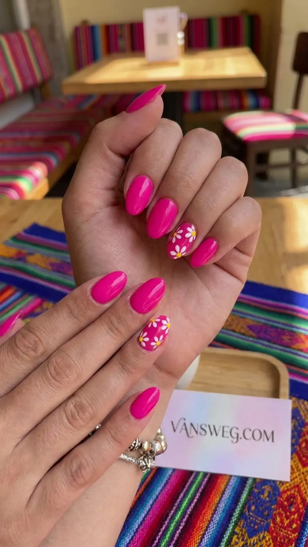 Vibrant neon fuchsia pink oval nails featuring playful hand-painted white daisy accents by VANSWEG.COM.