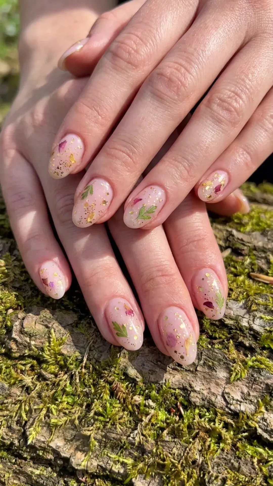Nature-inspired nails with a base of soft pink, delicately sprinkled with golden flecks resembling pollen from a blooming flower