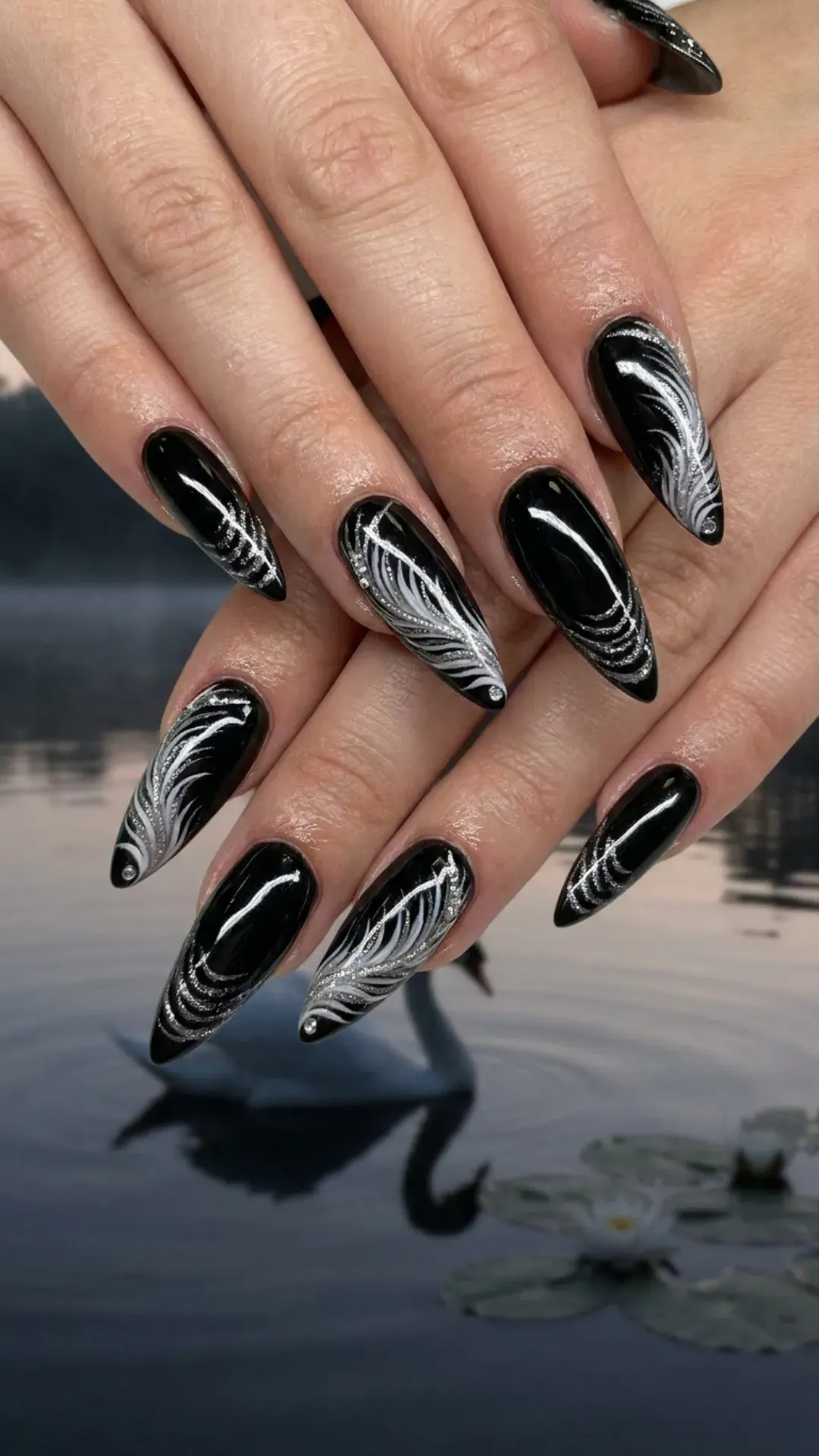Elegant stiletto nails featuring a black base with delicate white and silver glitter accents, resembling the grace of a swan on a tranquil lake.