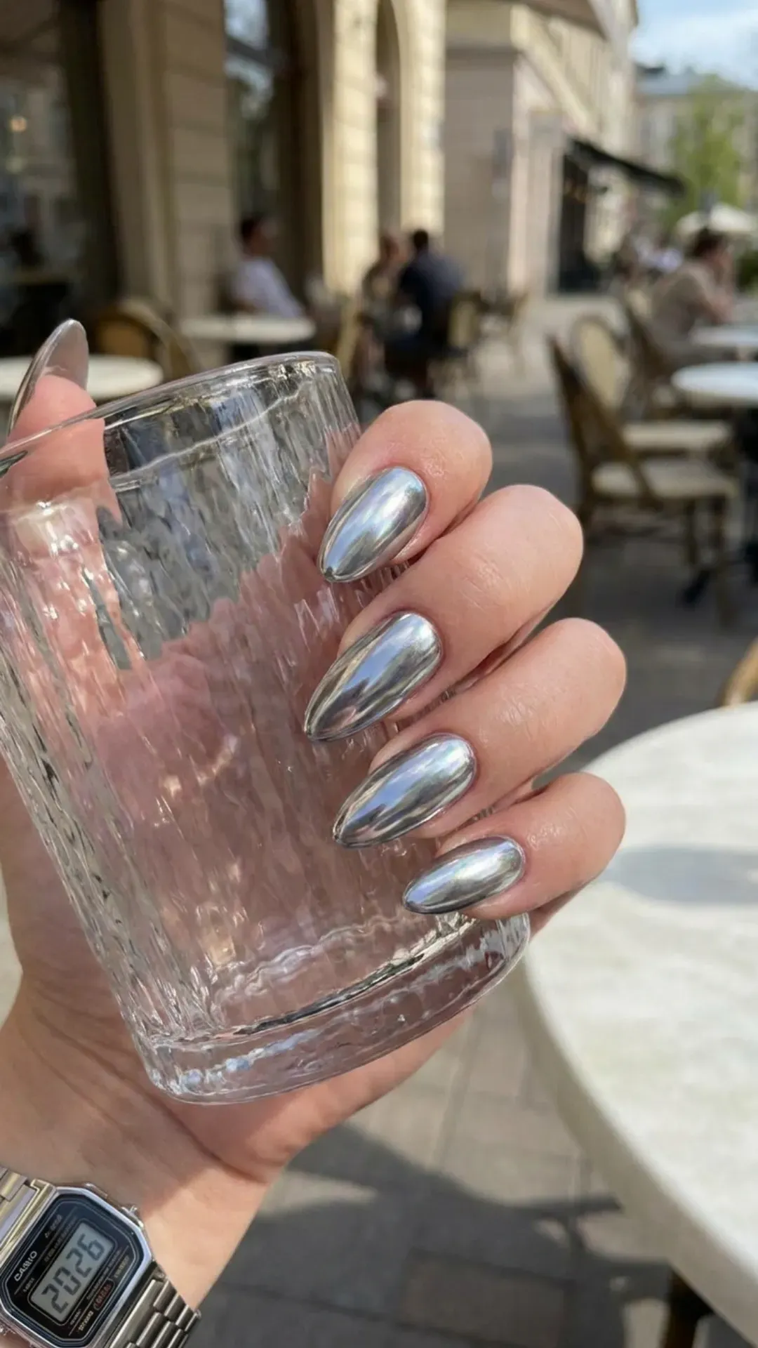 Hand with metallic silver nails, showcasing a futuristic and reflective color trend for summer 2026.