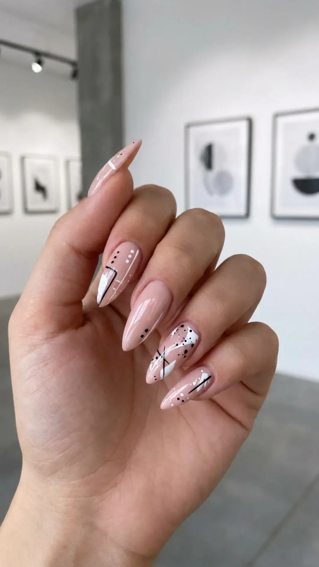 Stiletto nails featuring a nude pink base, with an abstract design in white and black, adding a touch of modern art to a sophisticated nail style.