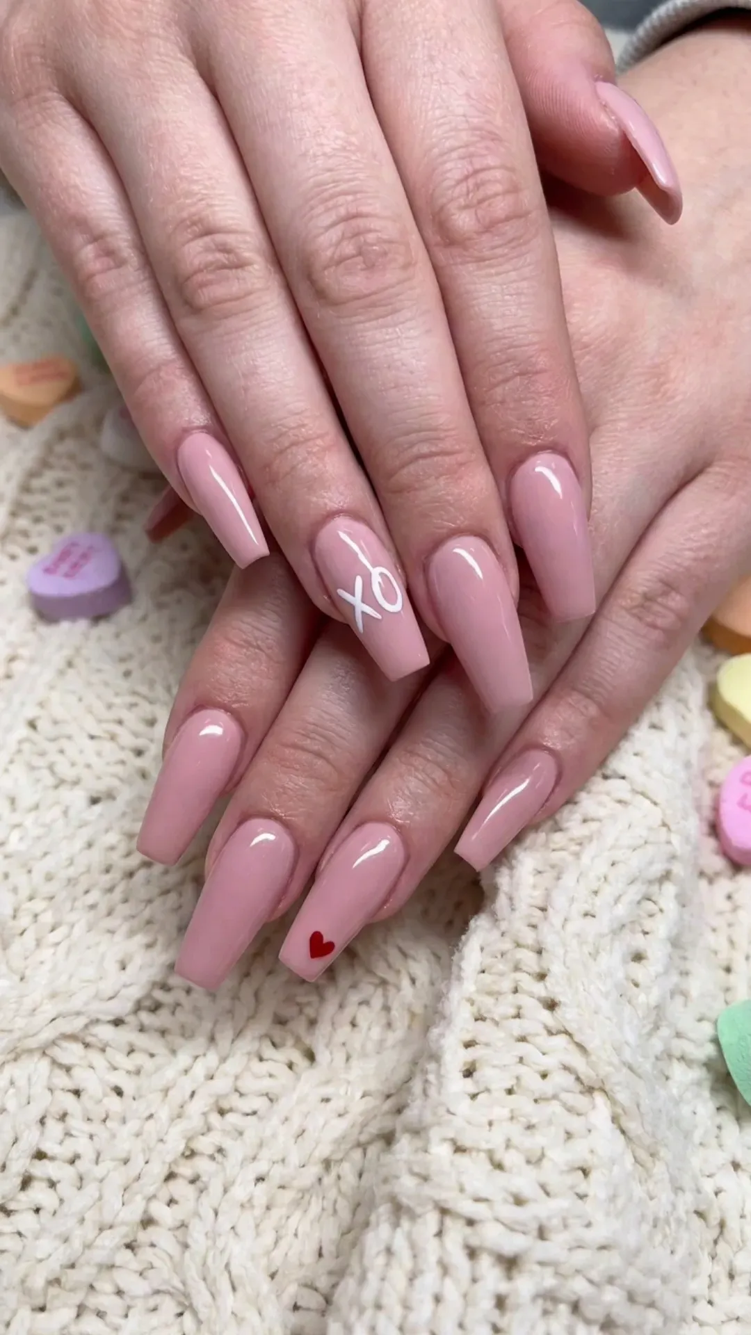 Fun-loving coffin nails with a soft pink base, adorned with 'XO' and a tiny heart on the ring fingers, expressing a playful and affectionate style.