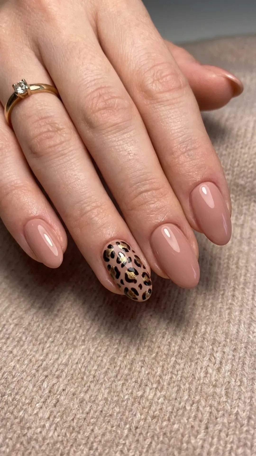 A chic set of nude pink nails featuring a bold leopard print accent nail for a touch of wild sophistication.