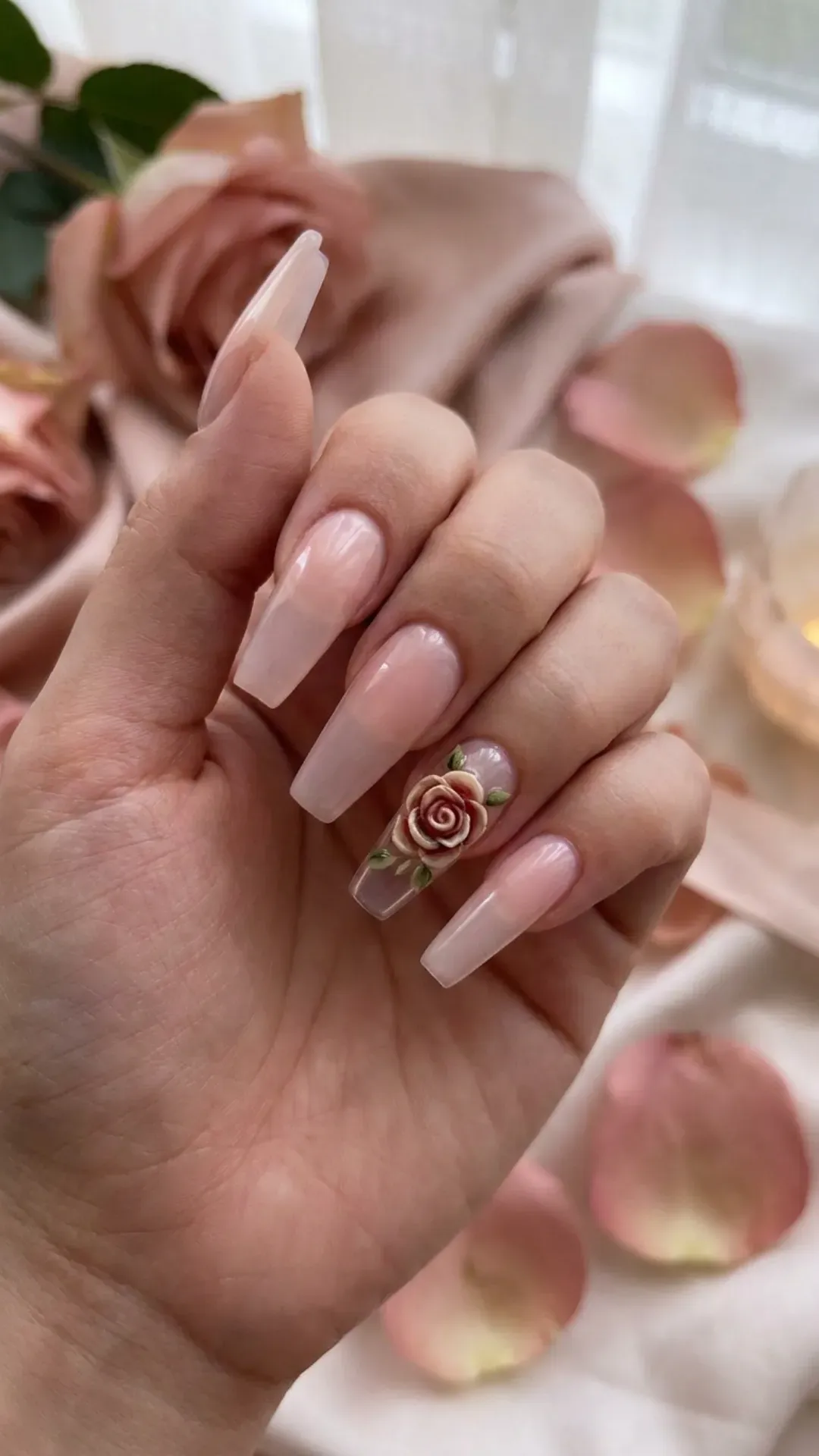 Translucent coffin nails with a single nail showcasing an intricately designed rose, set against a backdrop of soft pink shades for a romantic appeal.