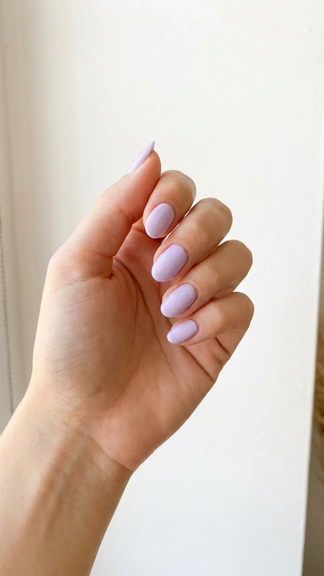 Hand with lavender nails against a white background, presenting a soft and pastel color ideal for summer 2026.