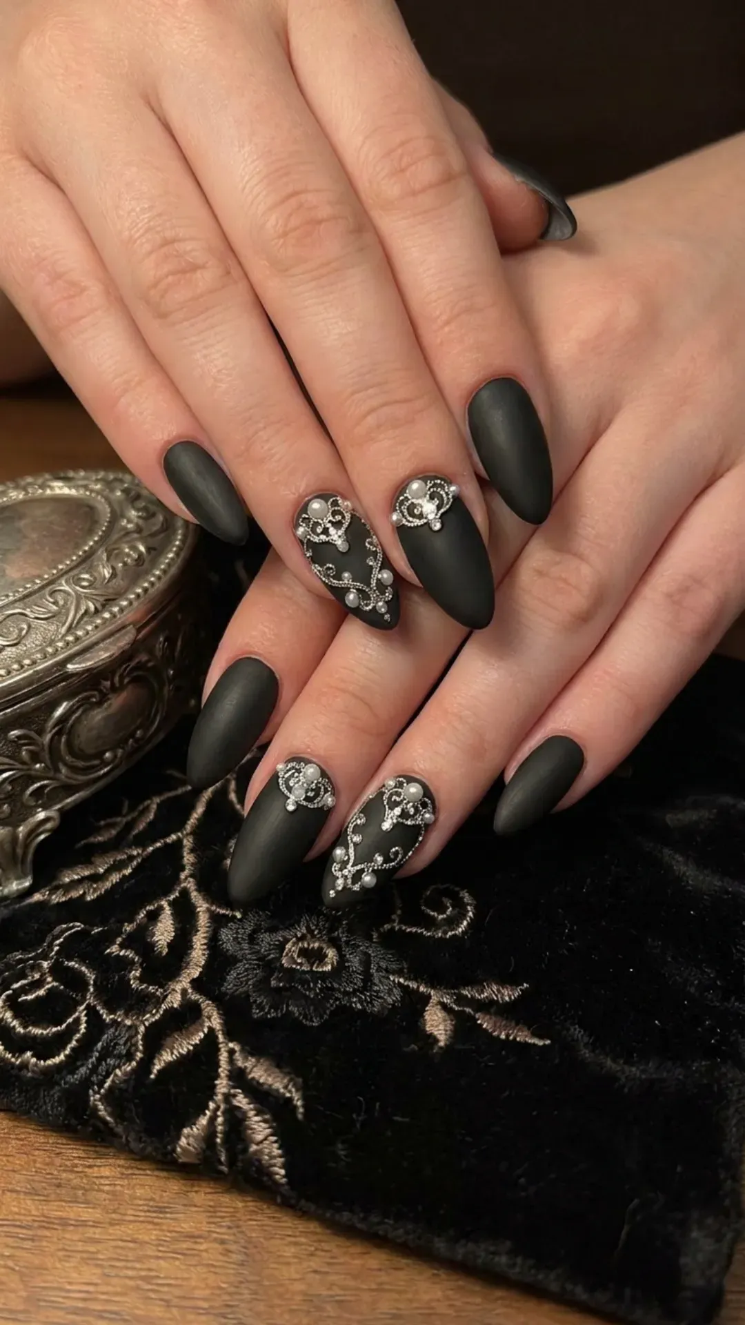 Sophisticated black matte nails adorned with intricate silver jewel embellishments, offering a touch of royal elegance.