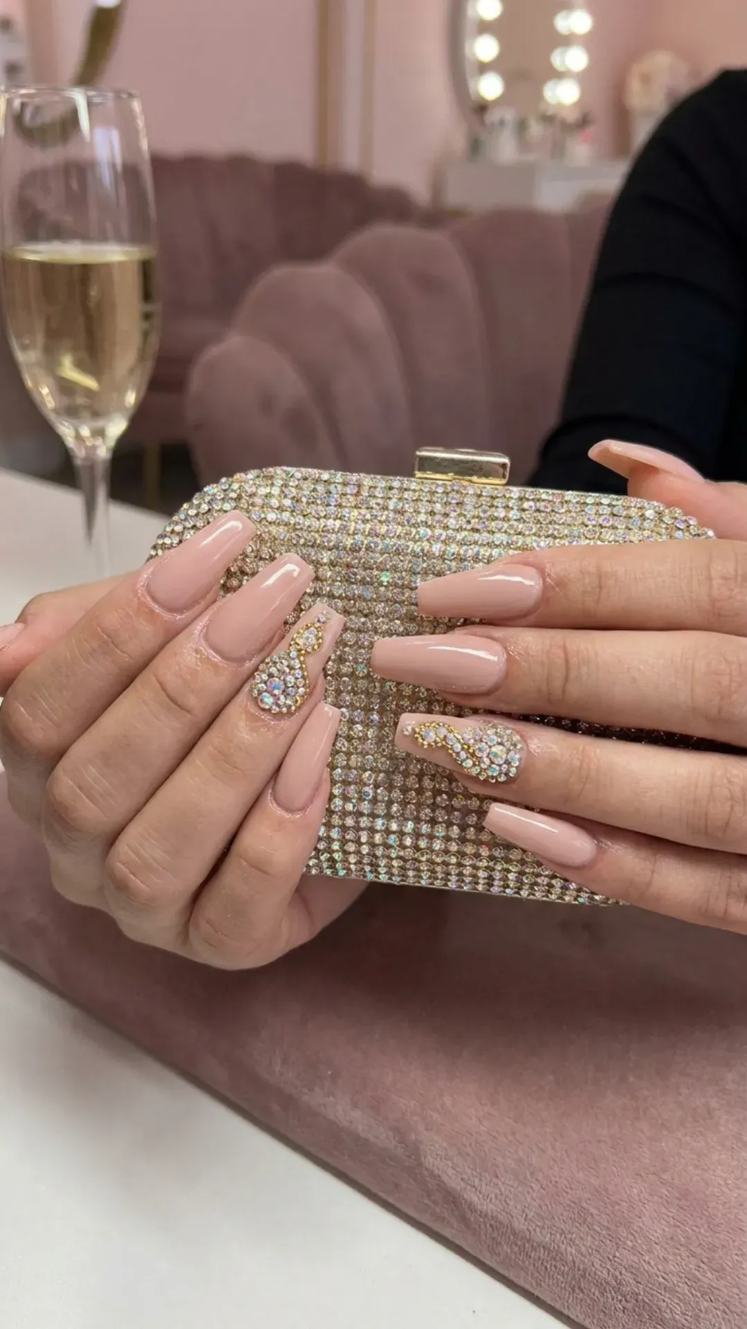  Luxurious nude pink nails with sparkling rhinestone embellishments creating a glamorous and sophisticated look.