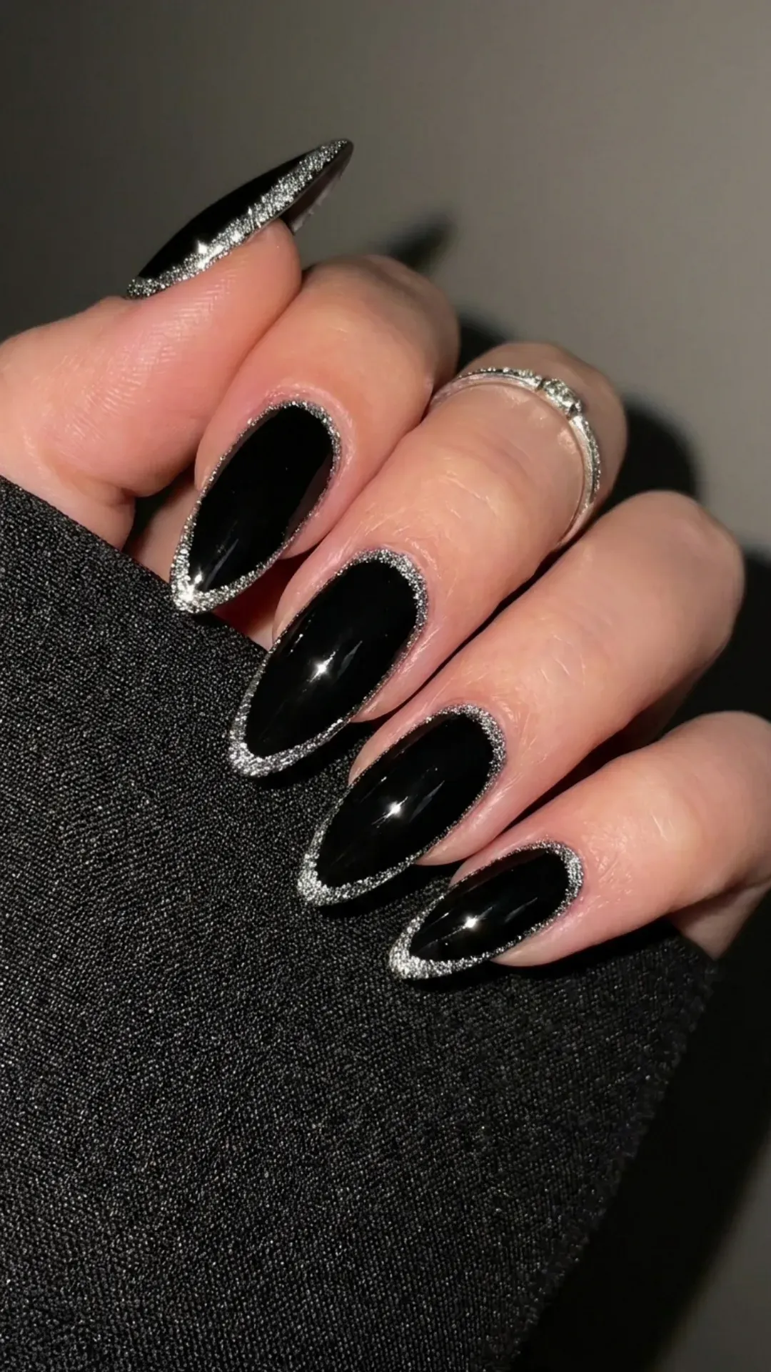 Chic black nails featuring a sparkling silver glitter outline, creating a mesmerizing contrast that’s both edgy and refined.