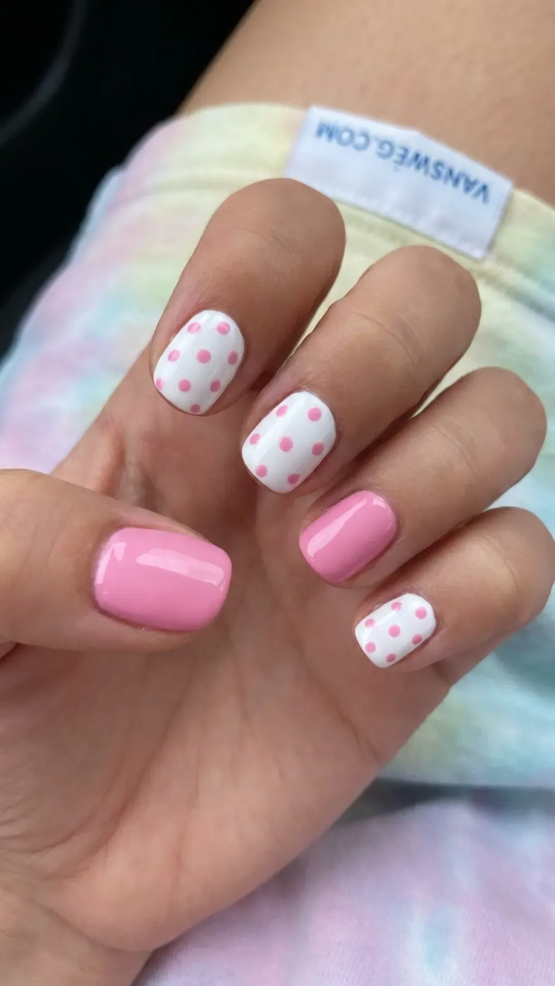 Playful short natural nails alternating between solid bubblegum pink and white with pink polka dots by VANSWEG.COM.
