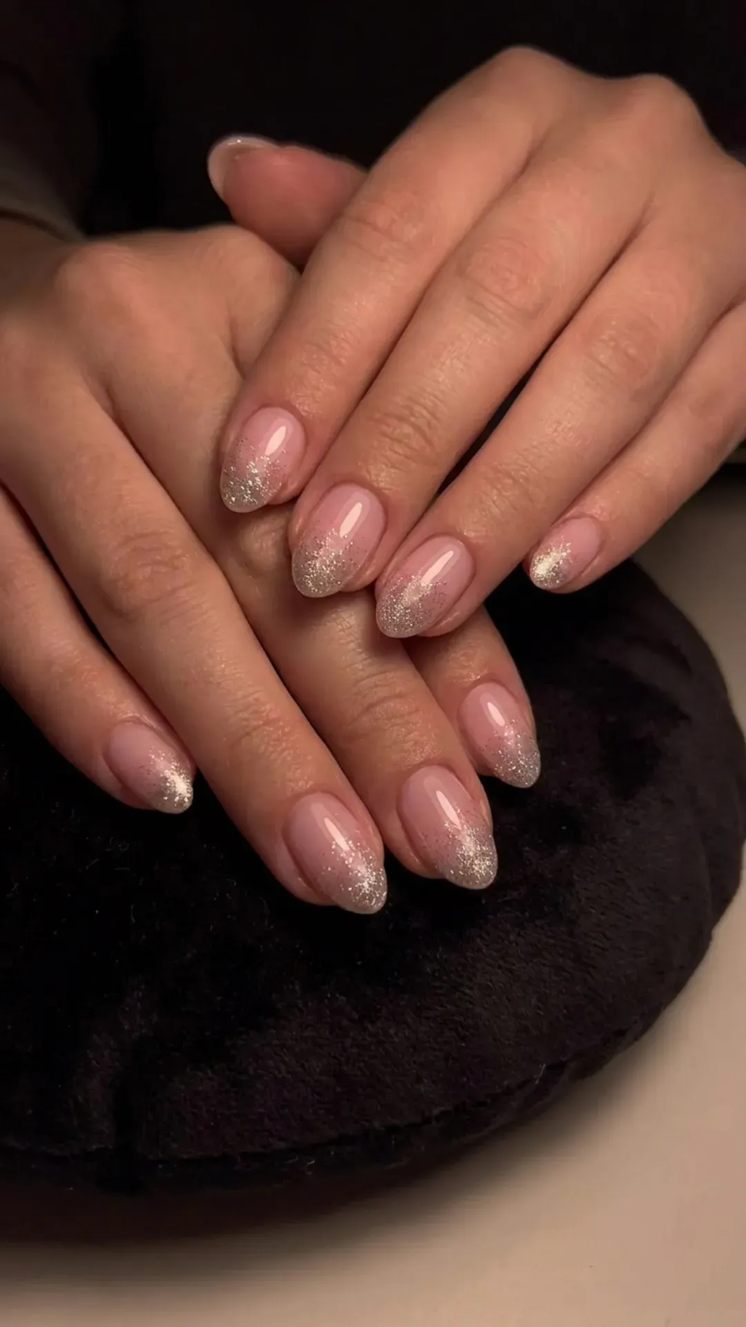 Chic nails painted in a soft pink hue with a feature of silvery glitter along the tips, creating a moonlit effect