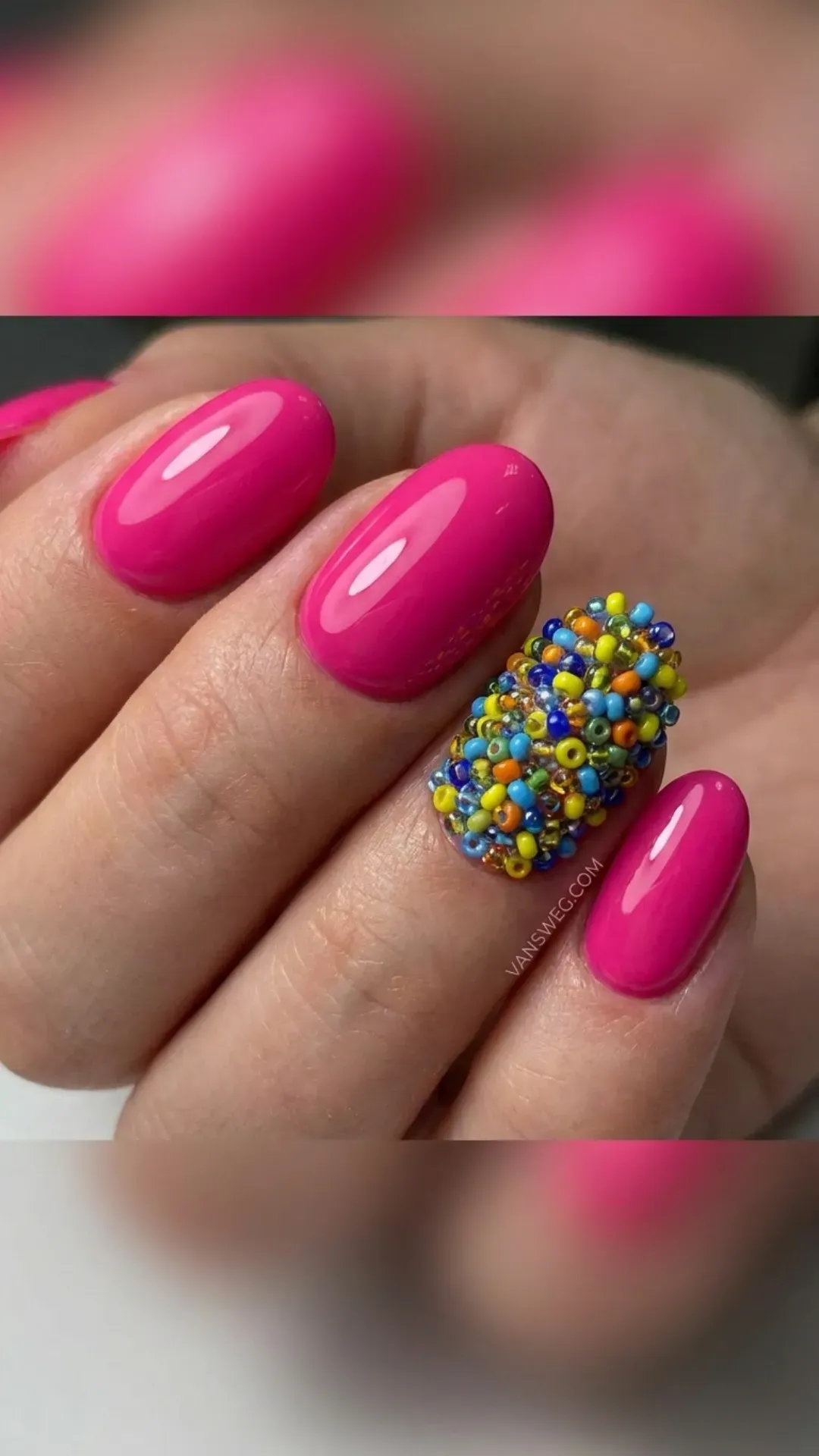 Glossy hot pink medium oval nails adorned with a bold, textured cluster of multi-colored seed beads by VANSWEG.COM.