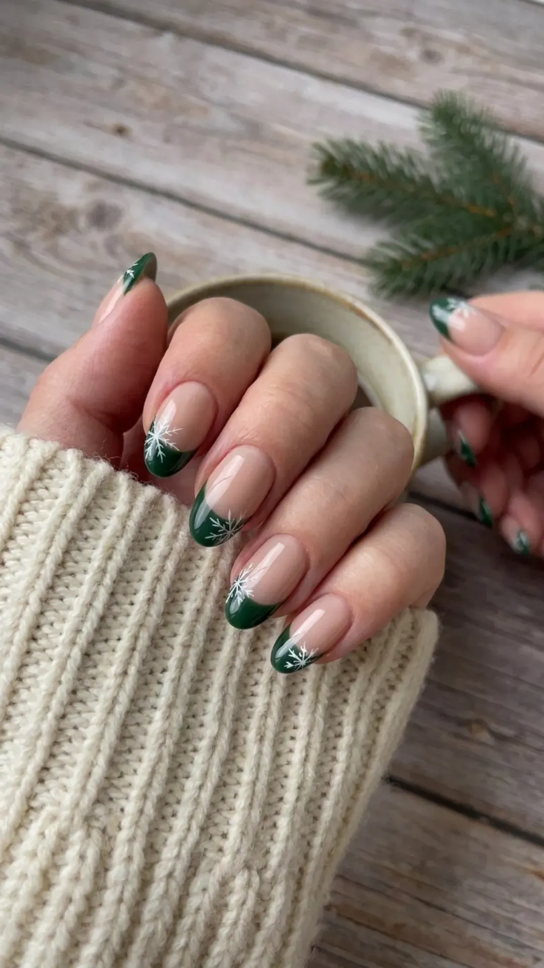 Chic combination of nude polish with winter green tips, adorned with delicate snowflake designs, blending natural tones with seasonal motifs.
