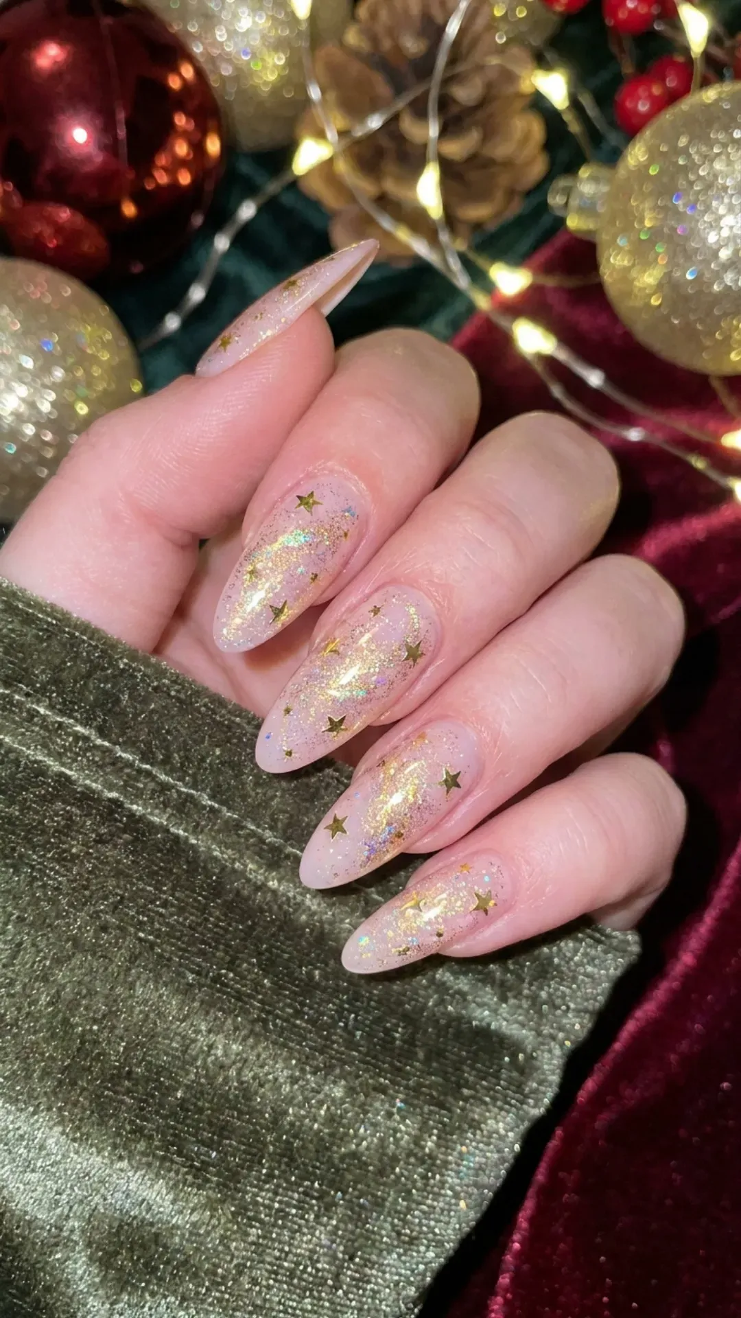 Dazzling and celestial, these light pink nails are sprinkled with delicate gold stars and a dusting of glitter, offering a dreamy night sky effect for the festive season.