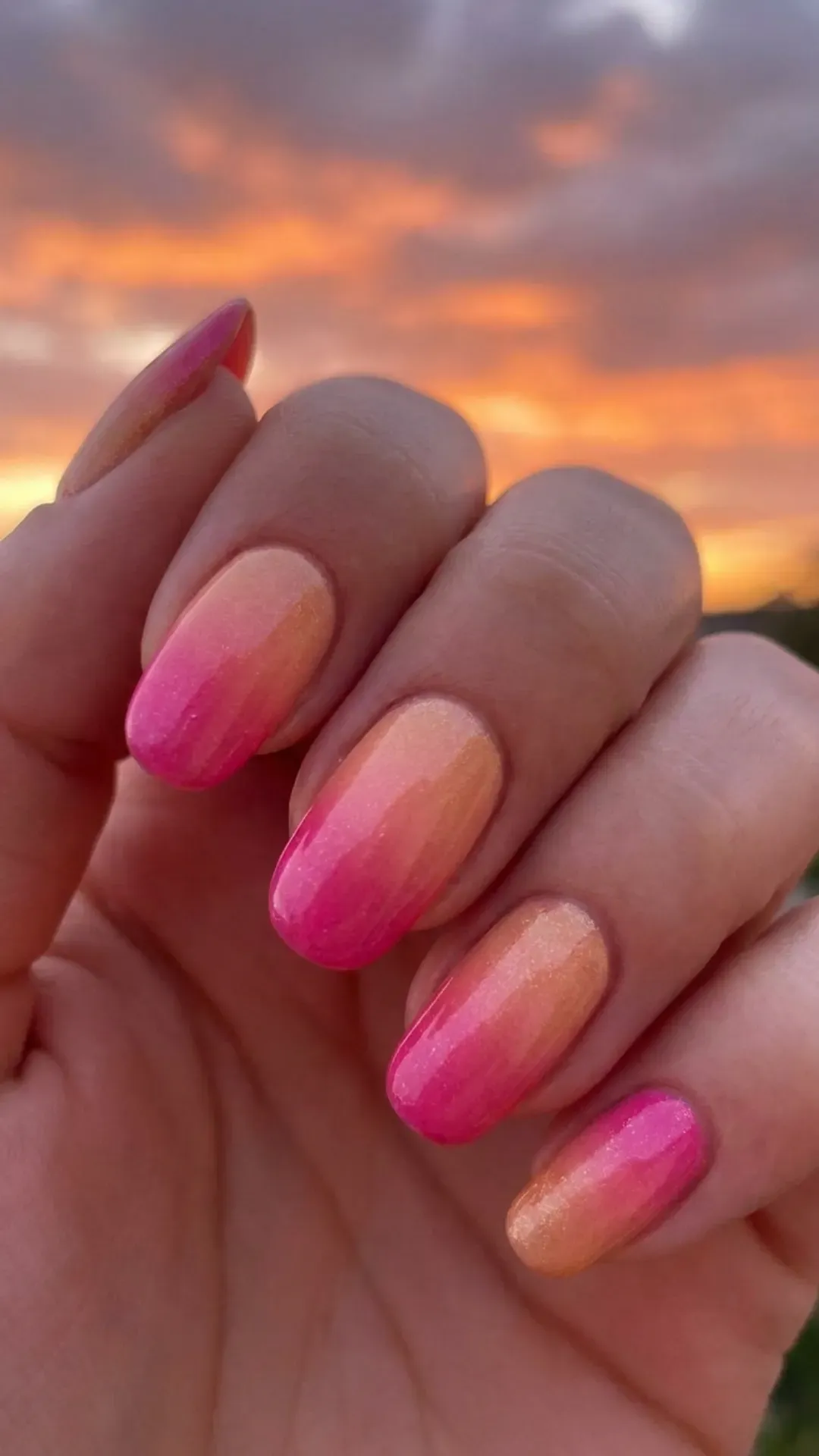 Nails with a stunning ombre effect transitioning from a bright pink to a softer tone, reflecting the vibrant colors of a sunset.