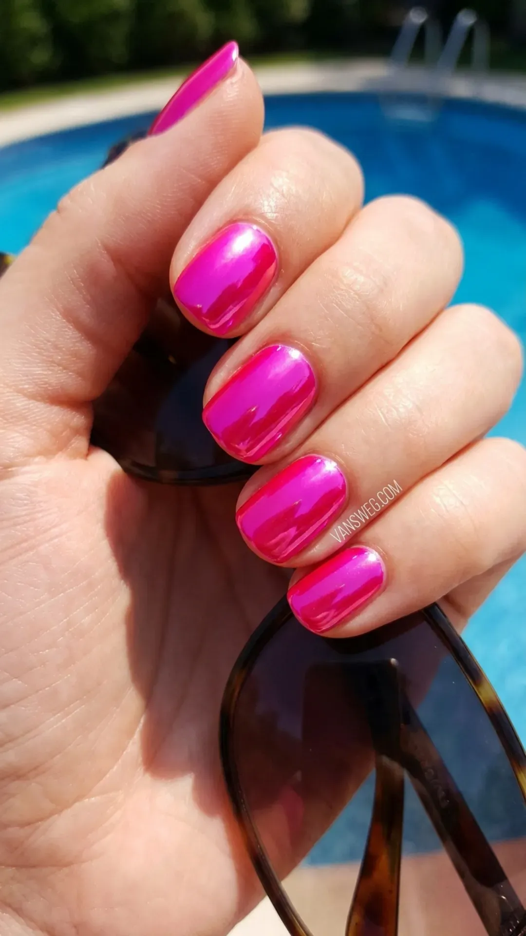 Vibrant bright hot pink rounded nails with a high-shine mirror glossy finish catching the summer sun by VANSWEG.COM.