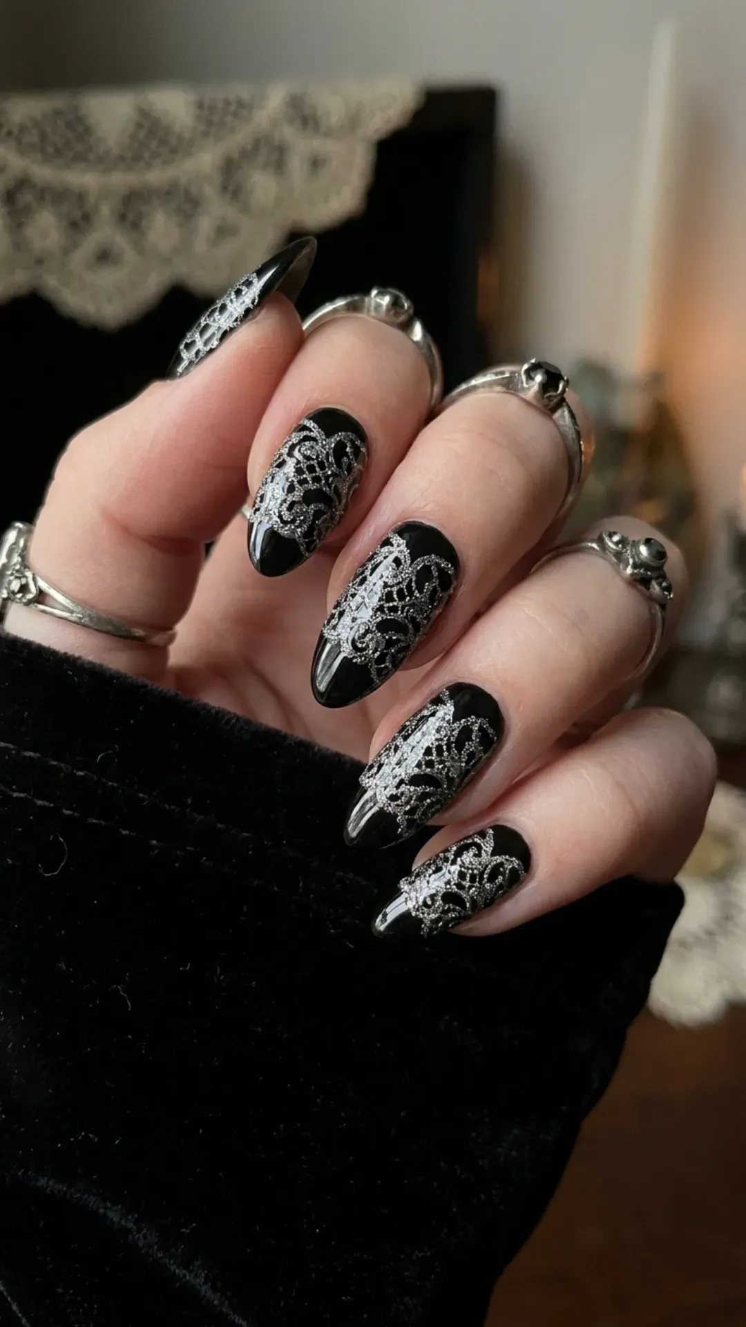 Unique black nails featuring a silver glitter design that mimics delicate lace, perfect for adding a touch of romantic intrigue to any look.