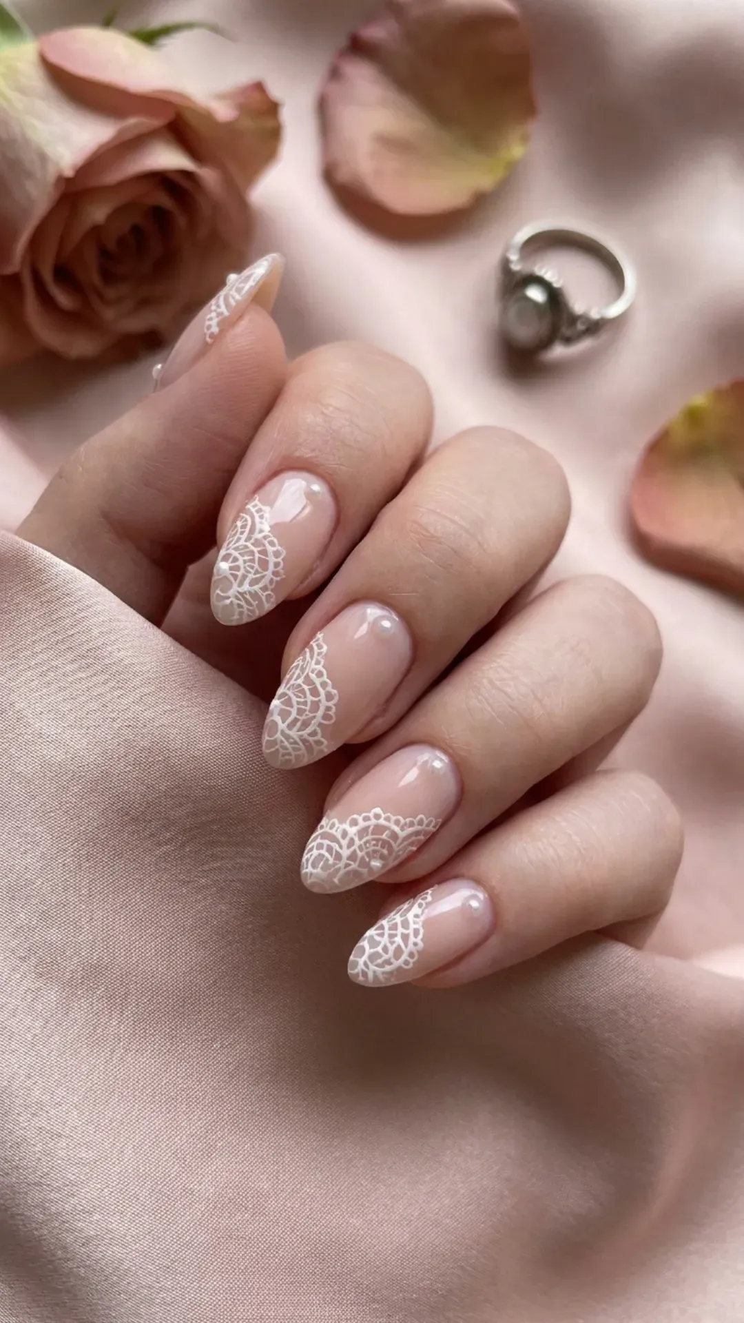 Nude pink nails adorned with intricate white lace designs, giving a romantic and feminine vibe to your nail art.