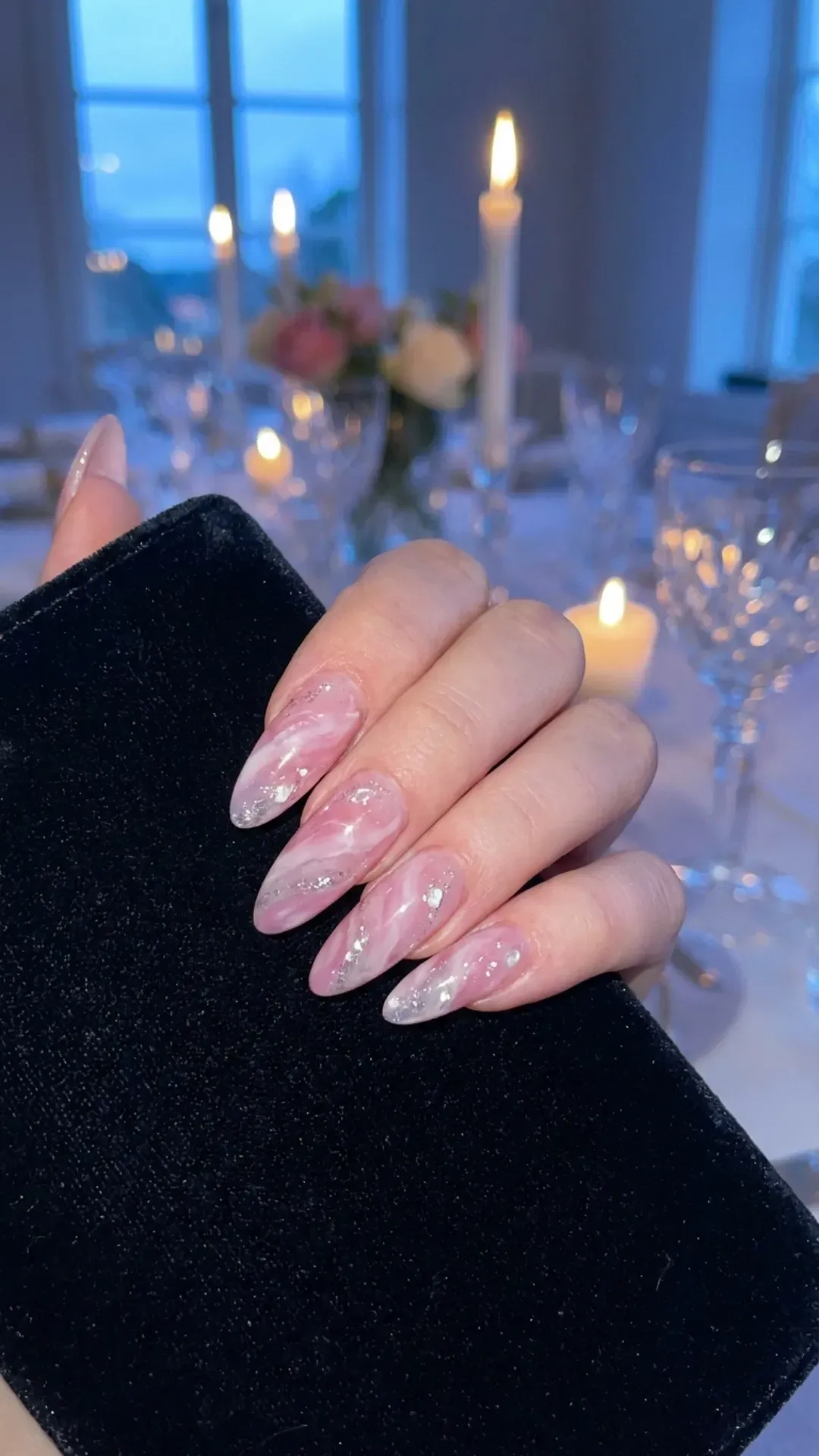 Sophisticated almond nails with a swirling pink and white marble effect, reminiscent of the gentle ripples in a swan lake under the winter moonlight, perfect for an elegant evening.