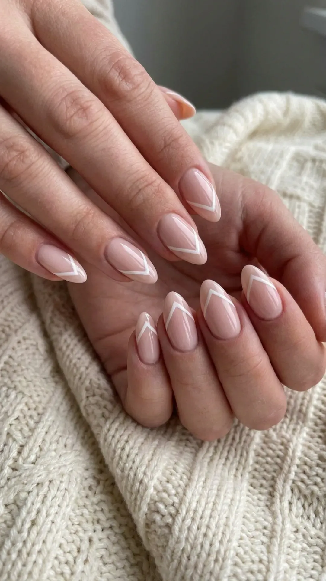 Nude pink nails with elegant chevron tips in white, creating a geometric contrast for a sharp and fashionable manicure.