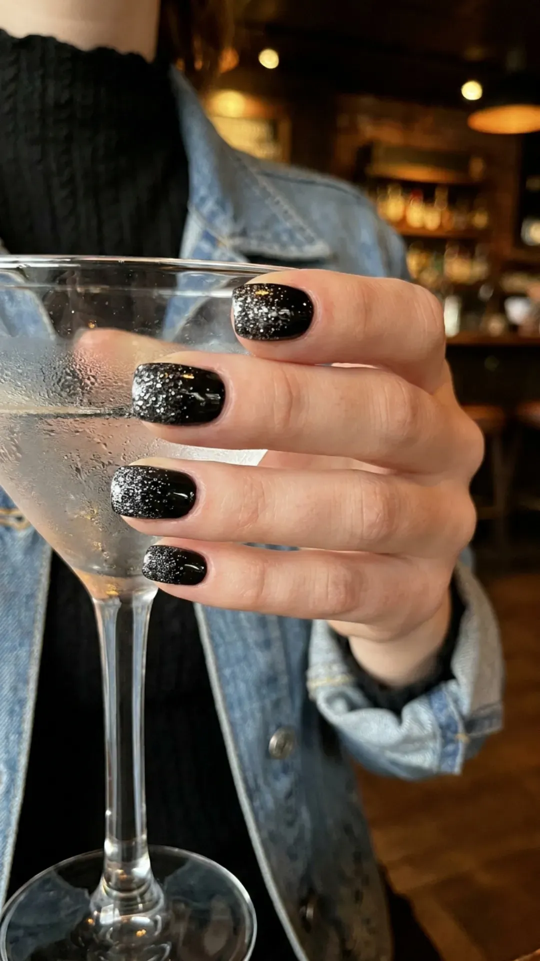 Short black nails with a scattered silver glitter gradation, creating a subtle yet sparkling effect, perfect for casual or evening wear.