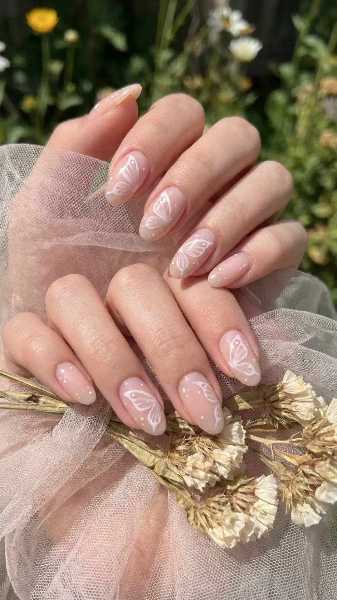 Delicate nude pink nails with white butterfly accents, providing a whimsical and airy touch to this dreamy manicure.