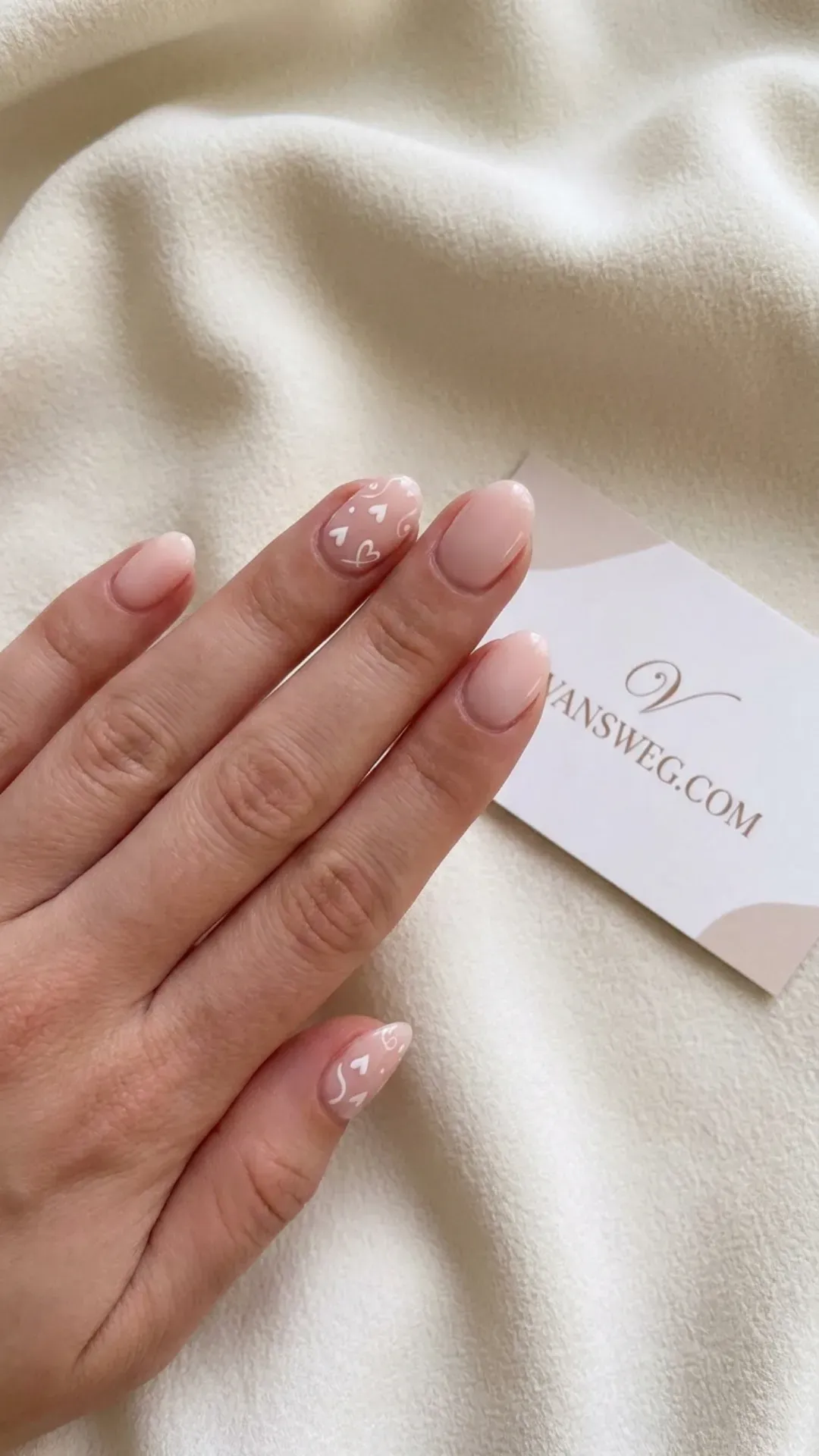 Short natural blush pink manicured nails with delicate, romantic hand-painted white heart accents by VANSWEG.COM.