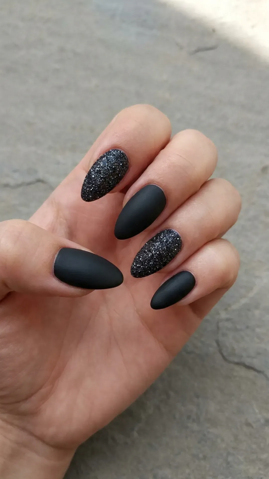 A mix of matte black and glitter-coated nails, showcasing a variety of textures with a uniform color scheme for a cohesive yet diverse nail design.