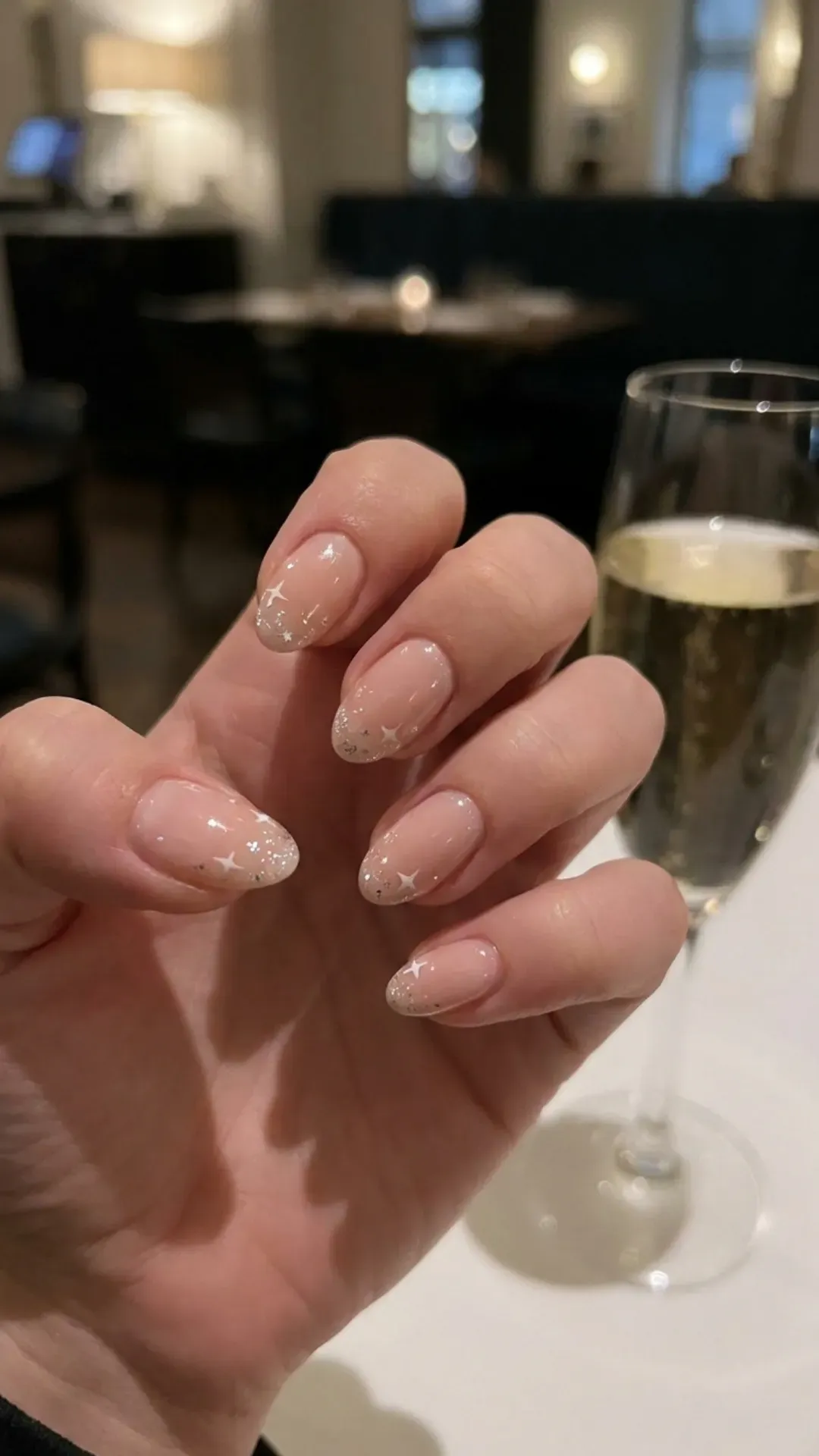 Dainty nude pink nails with a subtle starry sky design, featuring small white stars and glimmers, perfect for a night out or a sparkling everyday look.