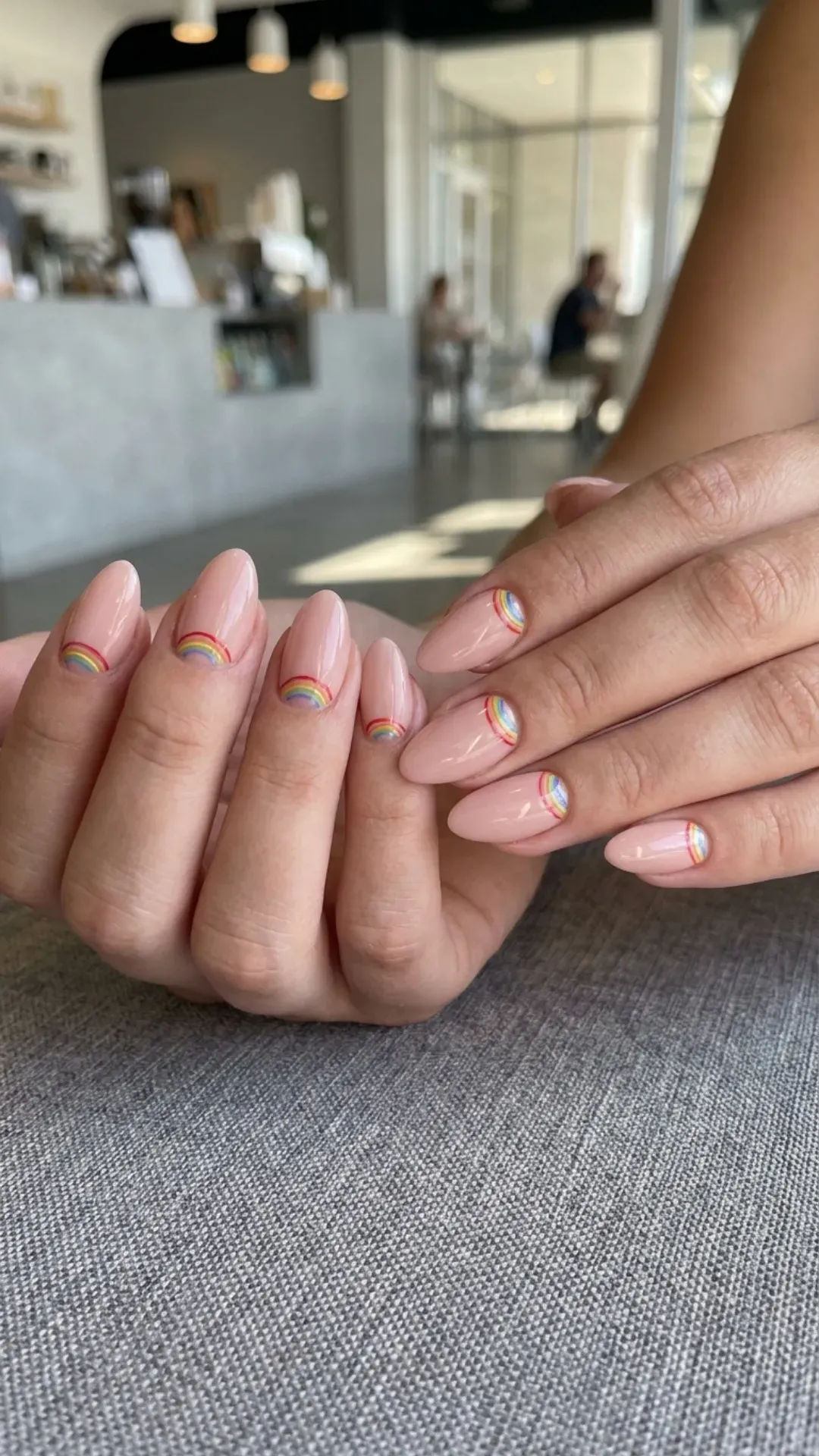 Fresh nude pink nails with playful rainbow accents on the cuticle, giving a subtle nod to pride with a stylish and modern manicure.