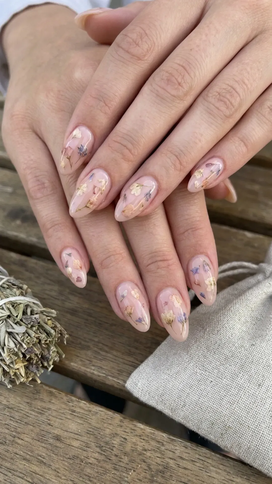 Unique nude pink nails with real dried flower accents encapsulated in clear polish, offering an organic and natural aesthetic to your nail art.