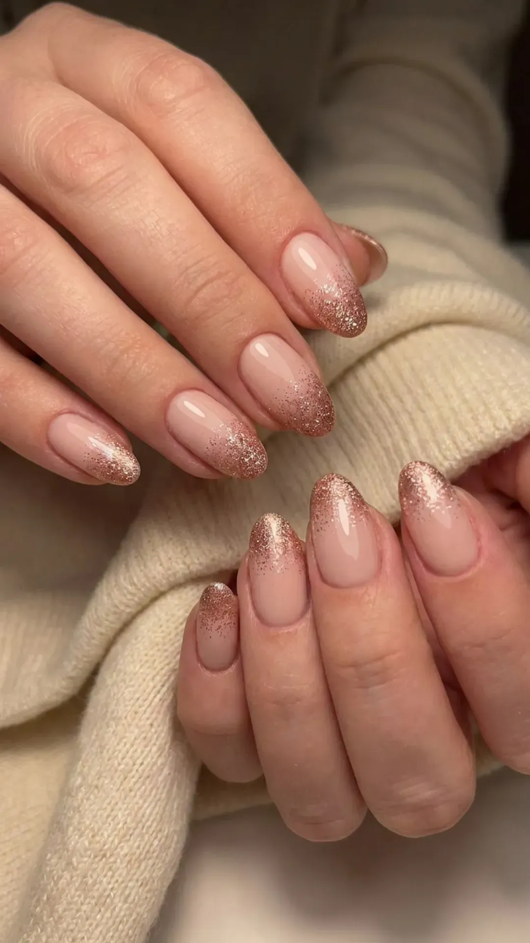 Soft nude pink nails with dazzling rose gold glitter tips, creating a gradient effect that adds sparkle and glamour to this fashionable manicure.