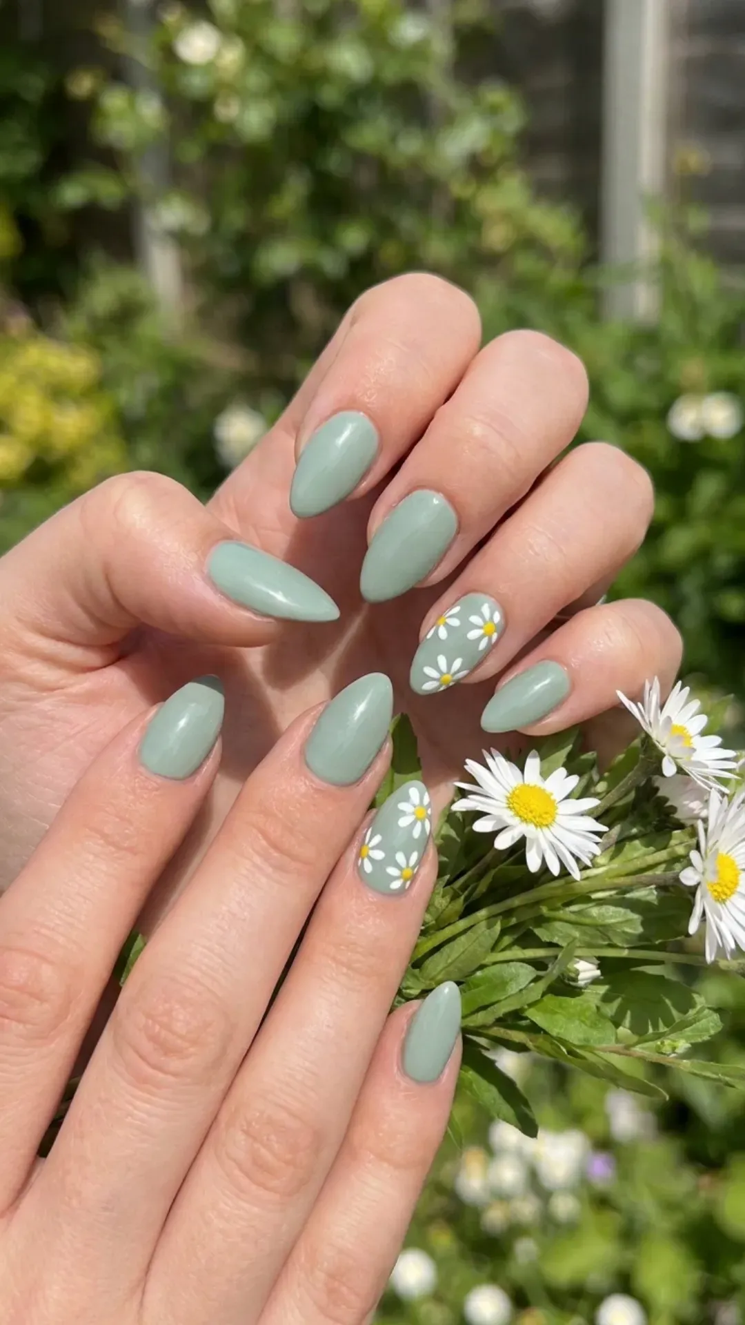 Short stiletto nails with a muted green base, featuring a minimalist daisy design in white, creating a fresh springtime look Flower Nails