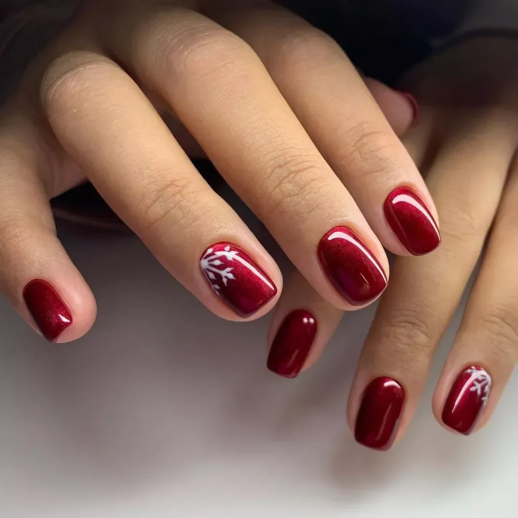 "Elegant deep red nails with a sleek snowflake design, adding a touch of winter magic to a traditional Christmas color."
