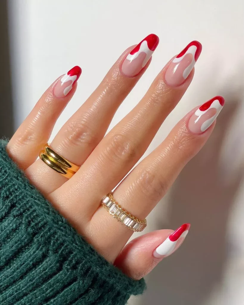 "Unique nail art design with alternating shades of red and white heart patterns on a translucent base, a creative take on the French manicure style."

