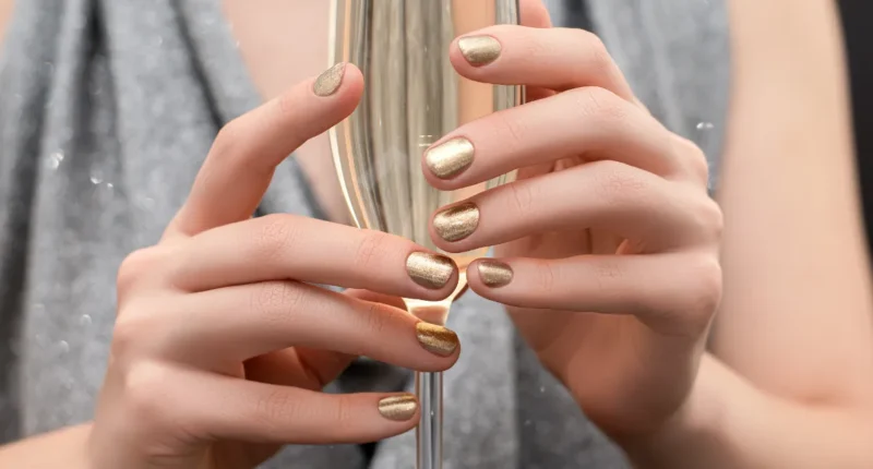 Close-up of hands with golden metallic nail polish, reflecting a shiny and luxurious finish perfect for elegant events