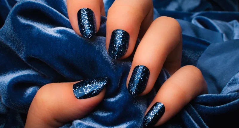 Dark blue nails with sparkling silver glitter, reminiscent of a starry night sky against luxurious blue velvet, for a glamorous January 2024 manicure.