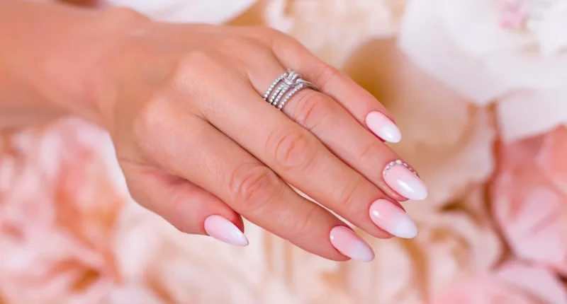 Elegant long nails with a blush to white ombre and delicate rhinestone embellishments, perfect for a sophisticated bridal look