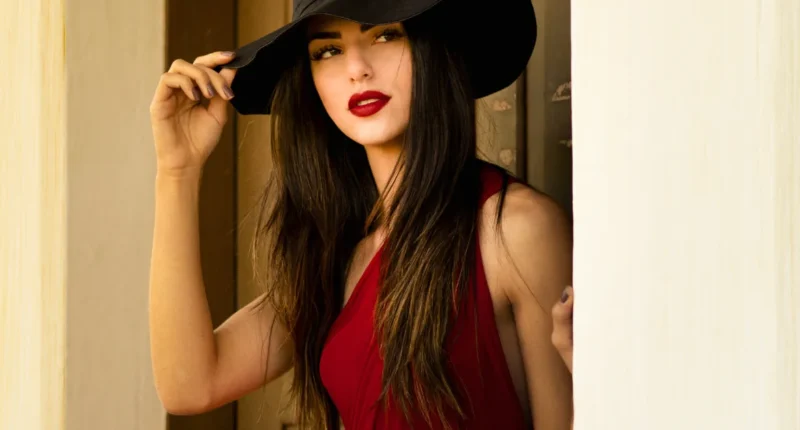 A bold and captivating Valentine's Day look featuring a woman in a deep red dress with a wide-brimmed black hat, exuding mystery and allure for a memorable occasion.