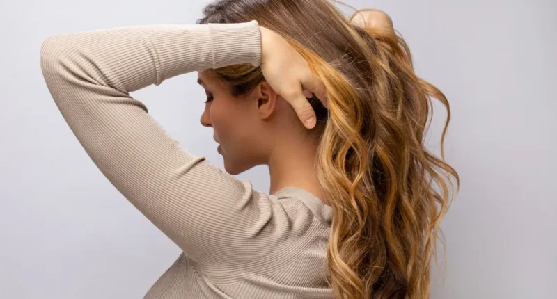 Casual yet chic ponytail hairstyle featuring caramel balayage with a blend of light and dark tones that enhance the playful curls and add a relaxed, effortless vibe.