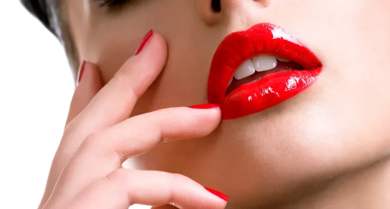 Close-up of red lips with glossy finish and matching red manicured nails, exemplifying a classic and bold makeup choice suitable for light skin tones